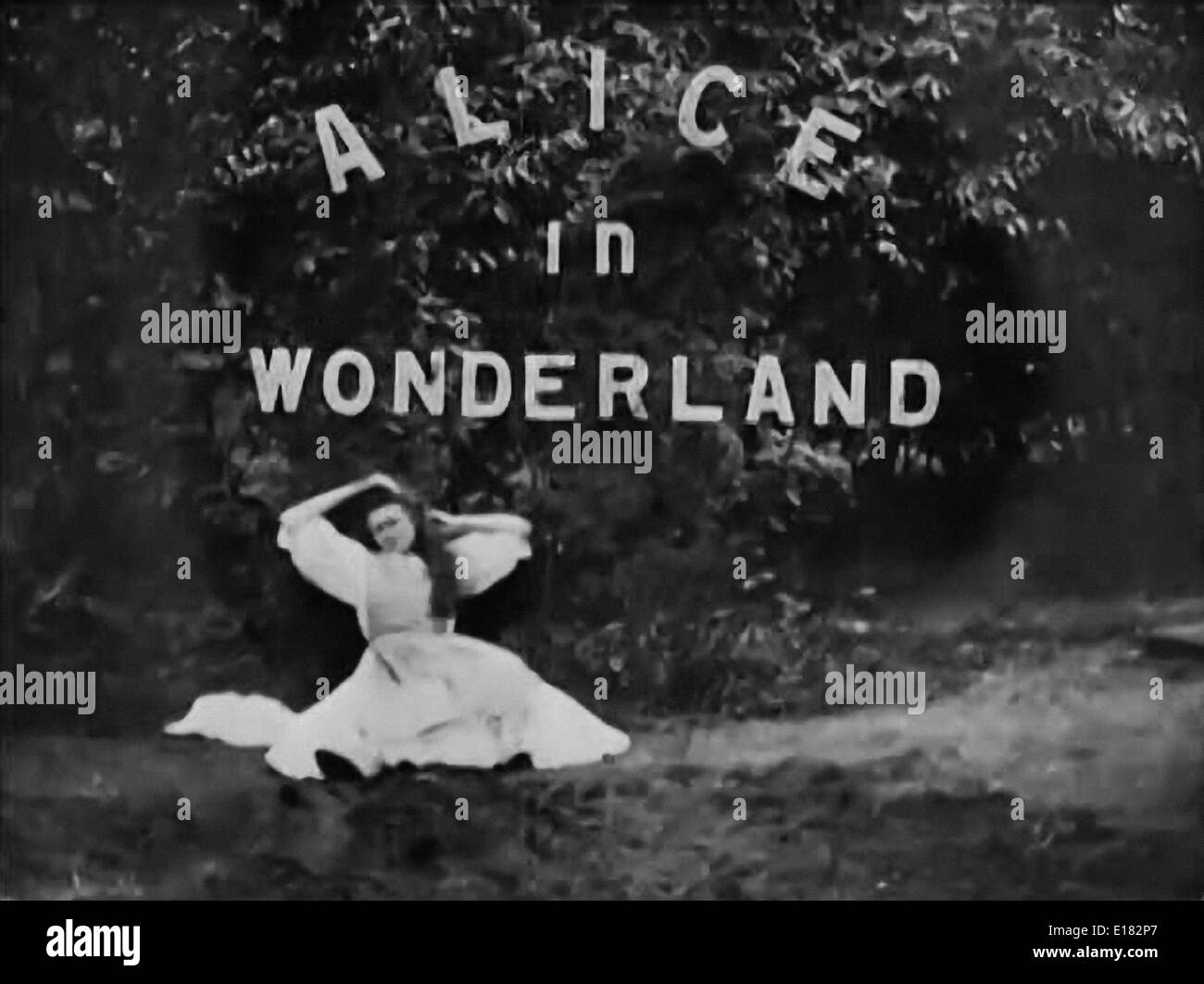 Still from 1903 movie adaptation of Lewis Carroll’s novel ‘Alice in Wonderland’ directed by Cecil M. Hepworth & Percy Stow. Starring May Clark as Alice and Mrs Hepworth as the Queen and White Rabbit. Still shows title, Alice about to fall to sleep and encounter the White Rabbit. Stock Photo