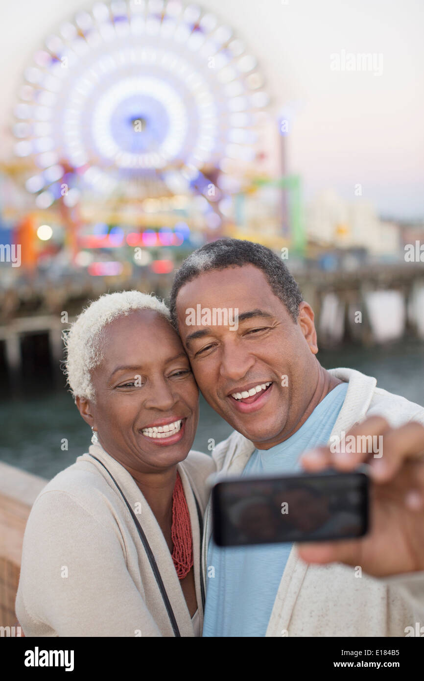 Senior couple taking selfie at amusement park Stock Photo