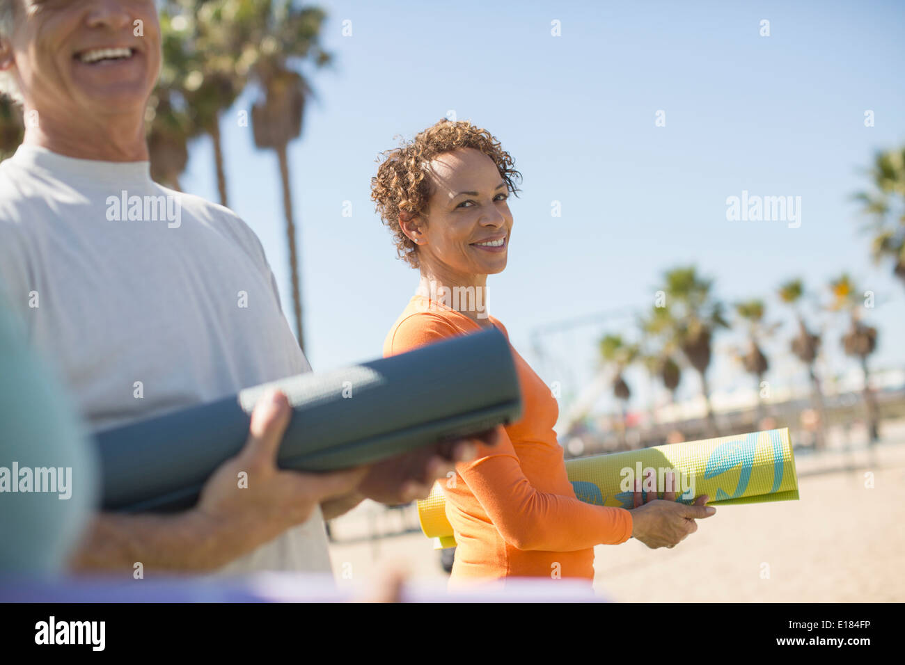 Portrait of smiling woman with yoga mat at beach Stock Photo