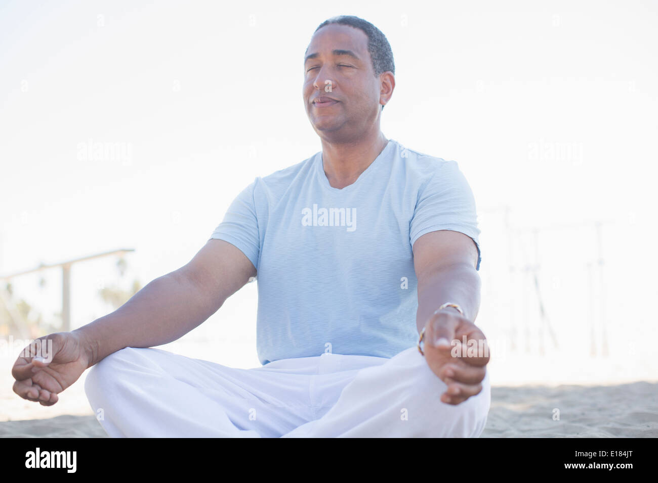 Serene senior man meditating in lotus position on beach Stock Photo