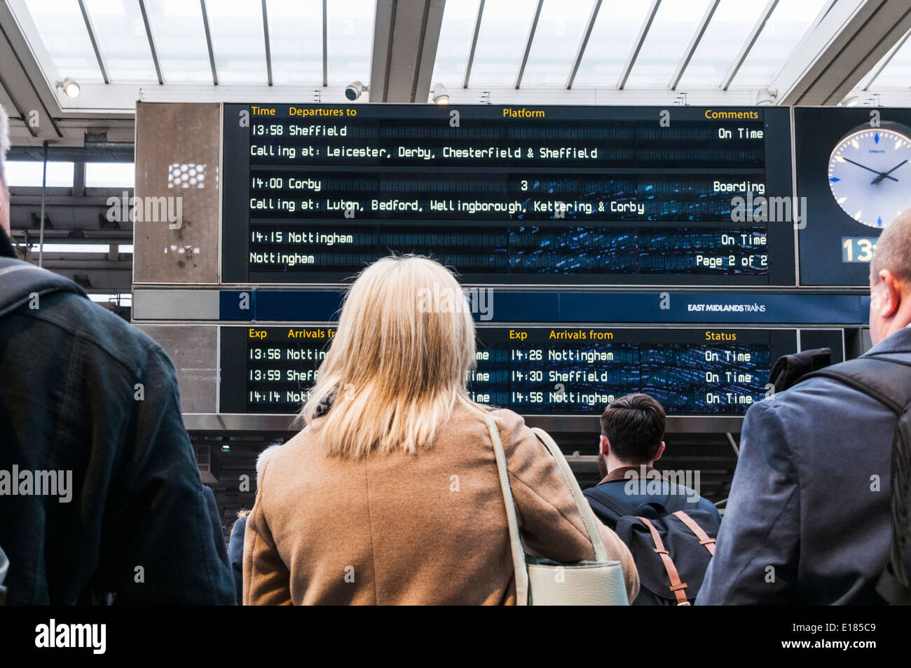 Backs of passengers standing looking up at the departures board at st Pancras train station in London Stock Photo