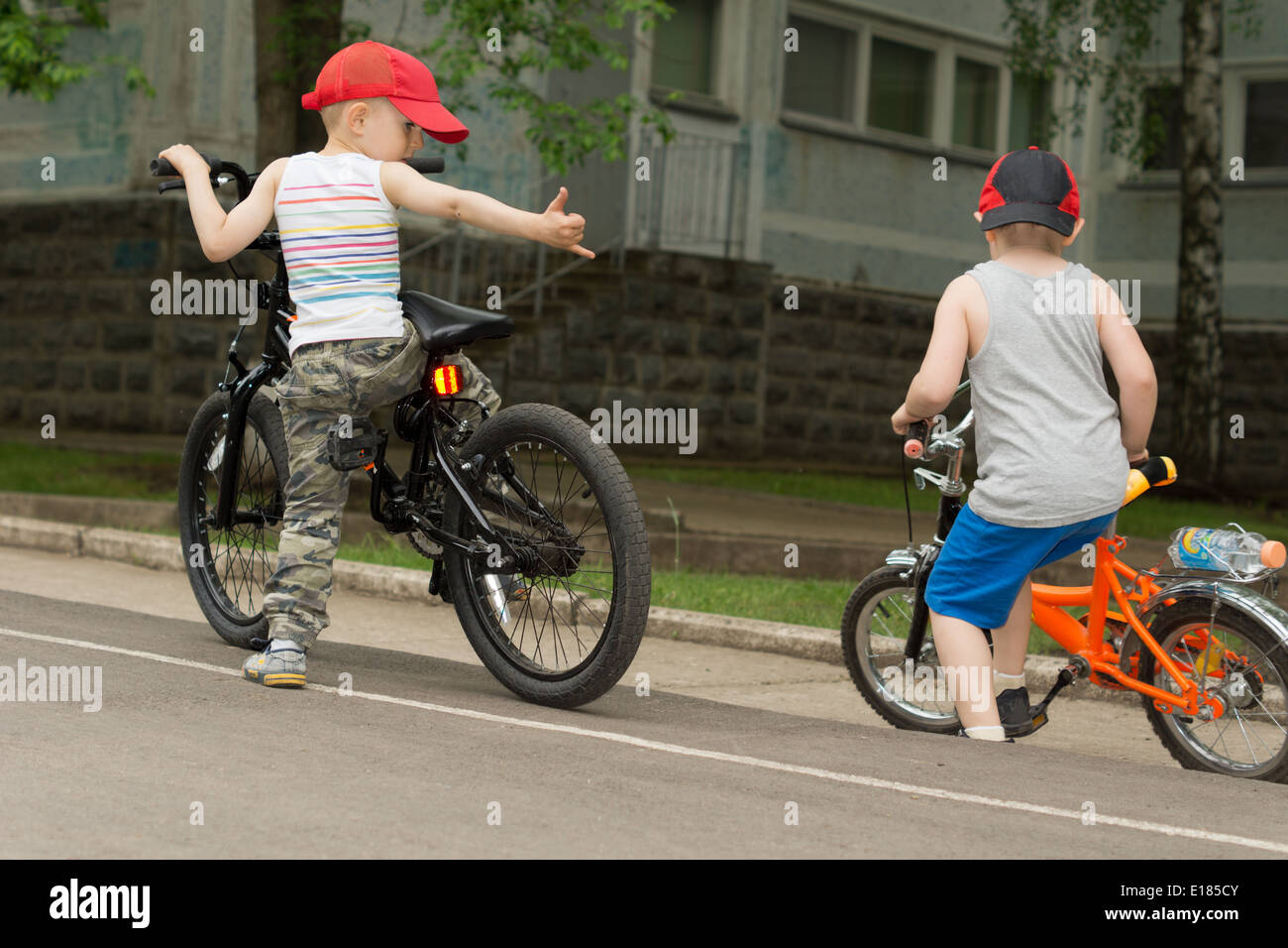 Two young boys playing together on their bikes at the side of the road in an urban environment Stock Photo