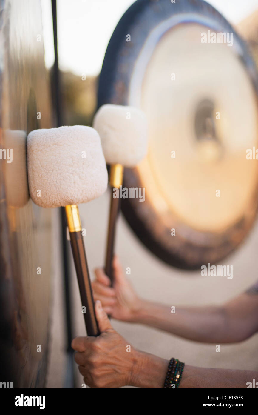 Sound bath gong healing. Hands striking the instrument with a mallet. Stock Photo