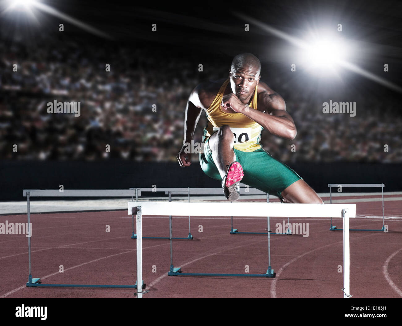 Runner clearing hurdle on track Stock Photo