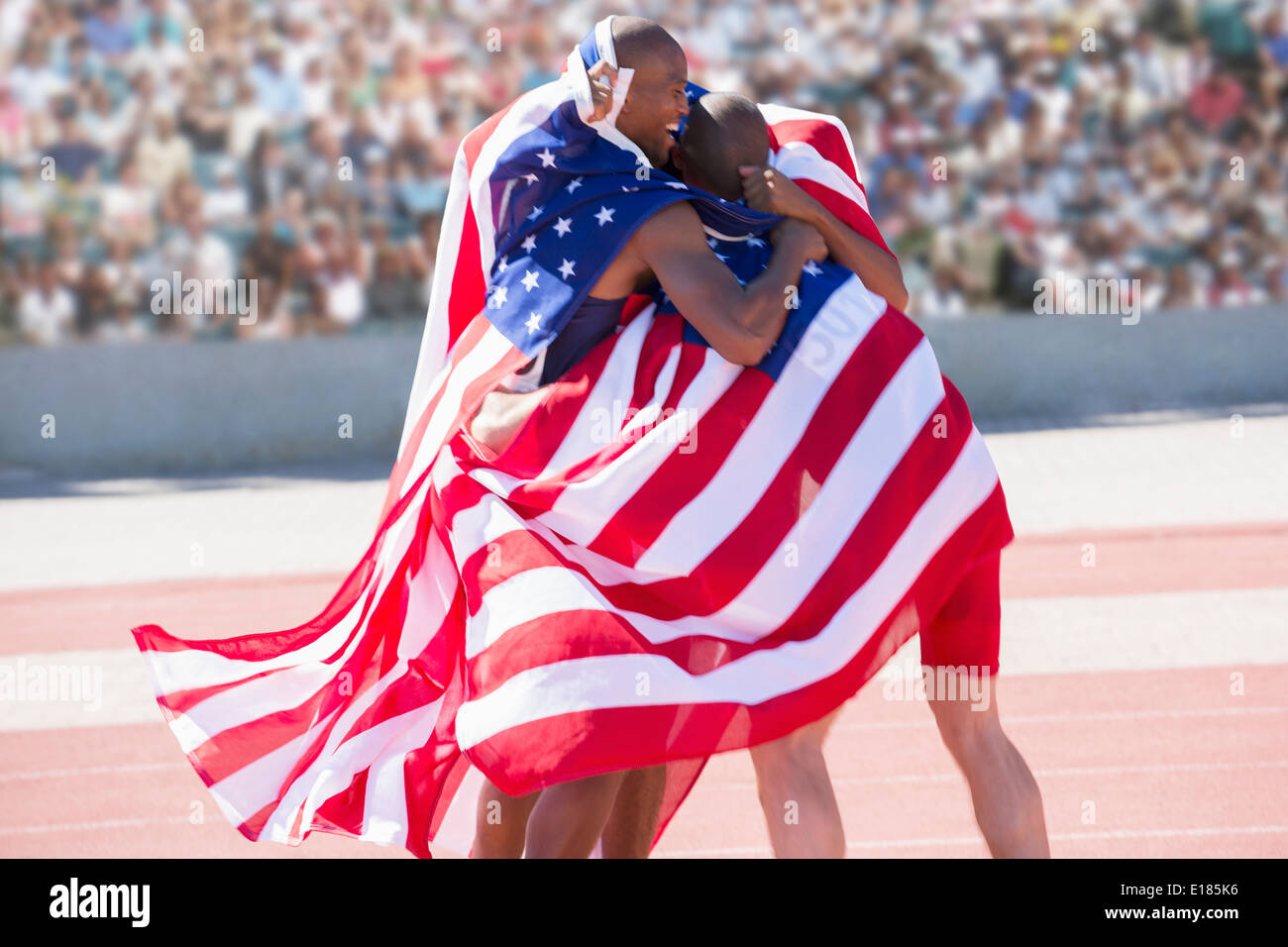 Track and field athletes wrapped in American flag on track Stock Photo