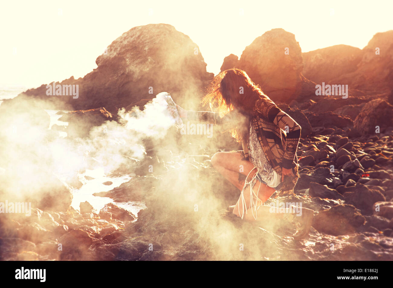 Smudge smoke offering on a rocky water seashore. Stock Photo