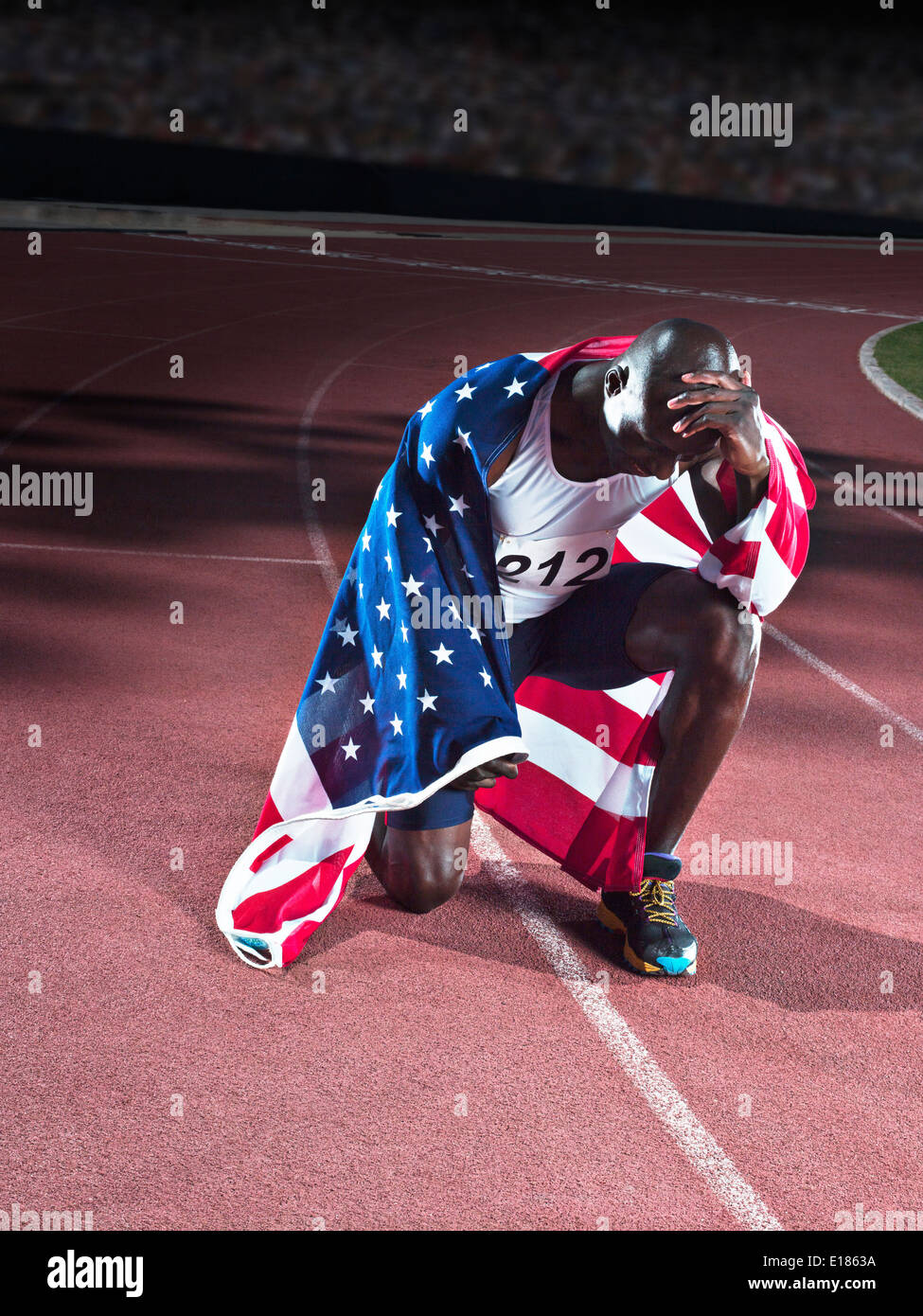 Track and field athlete wrapped in American flag on track Stock Photo
