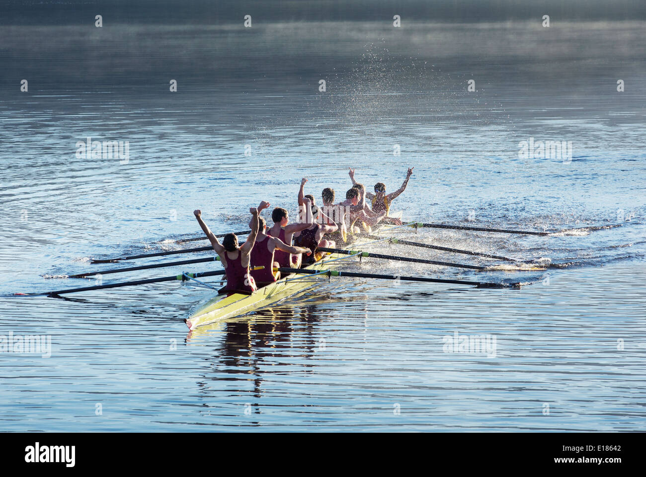Rowing team celebrating in scull on lake Stock Photo
