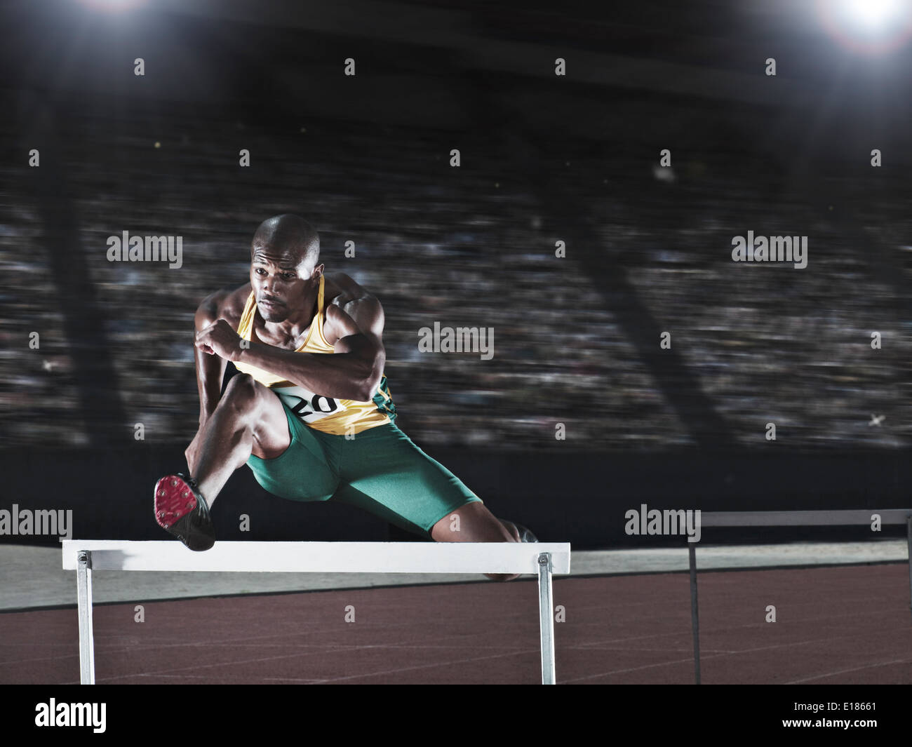 Runner jumping hurdle on track Stock Photo