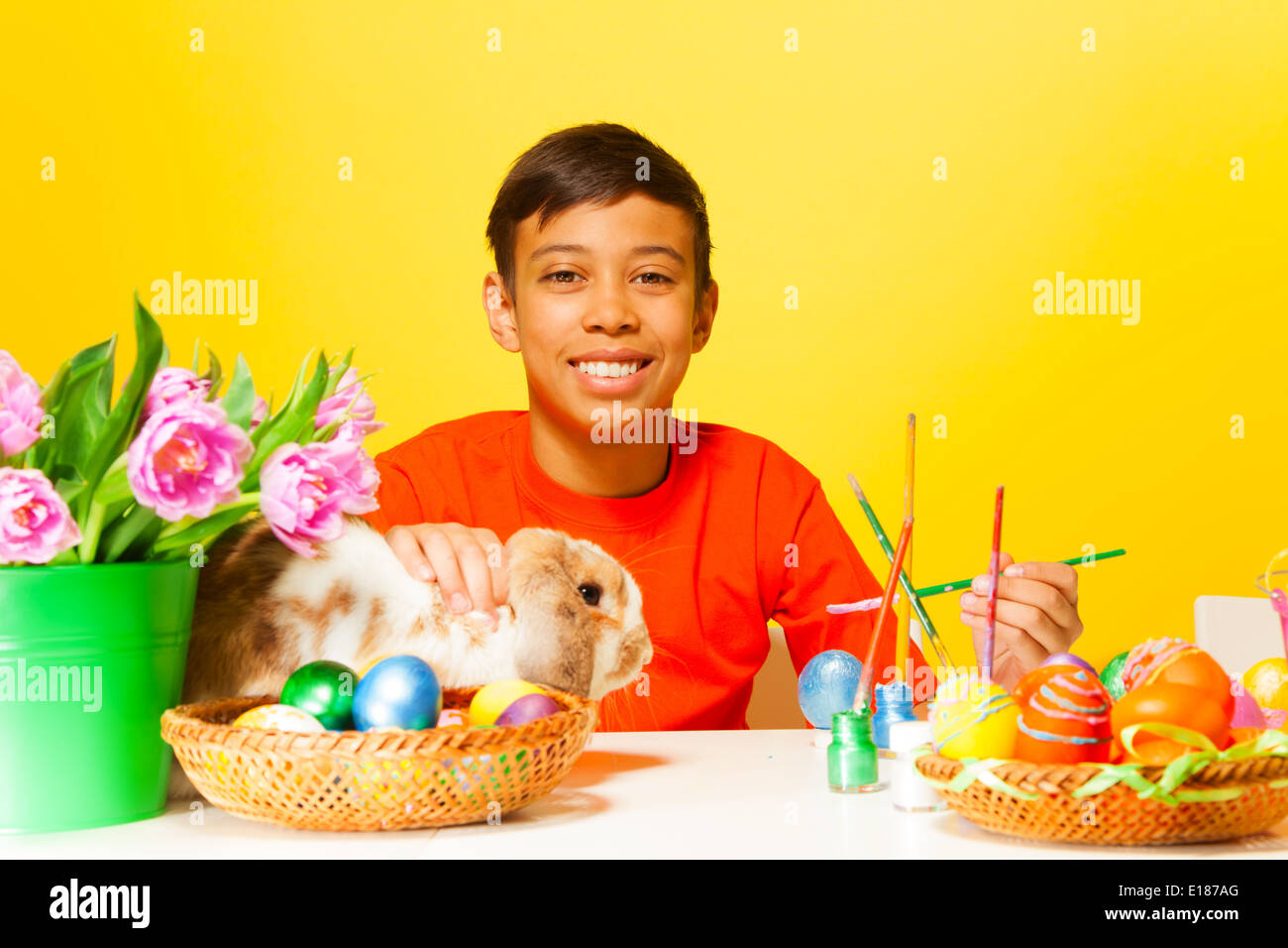 Boy paints Easter eggs with rabbit on the table Stock Photo