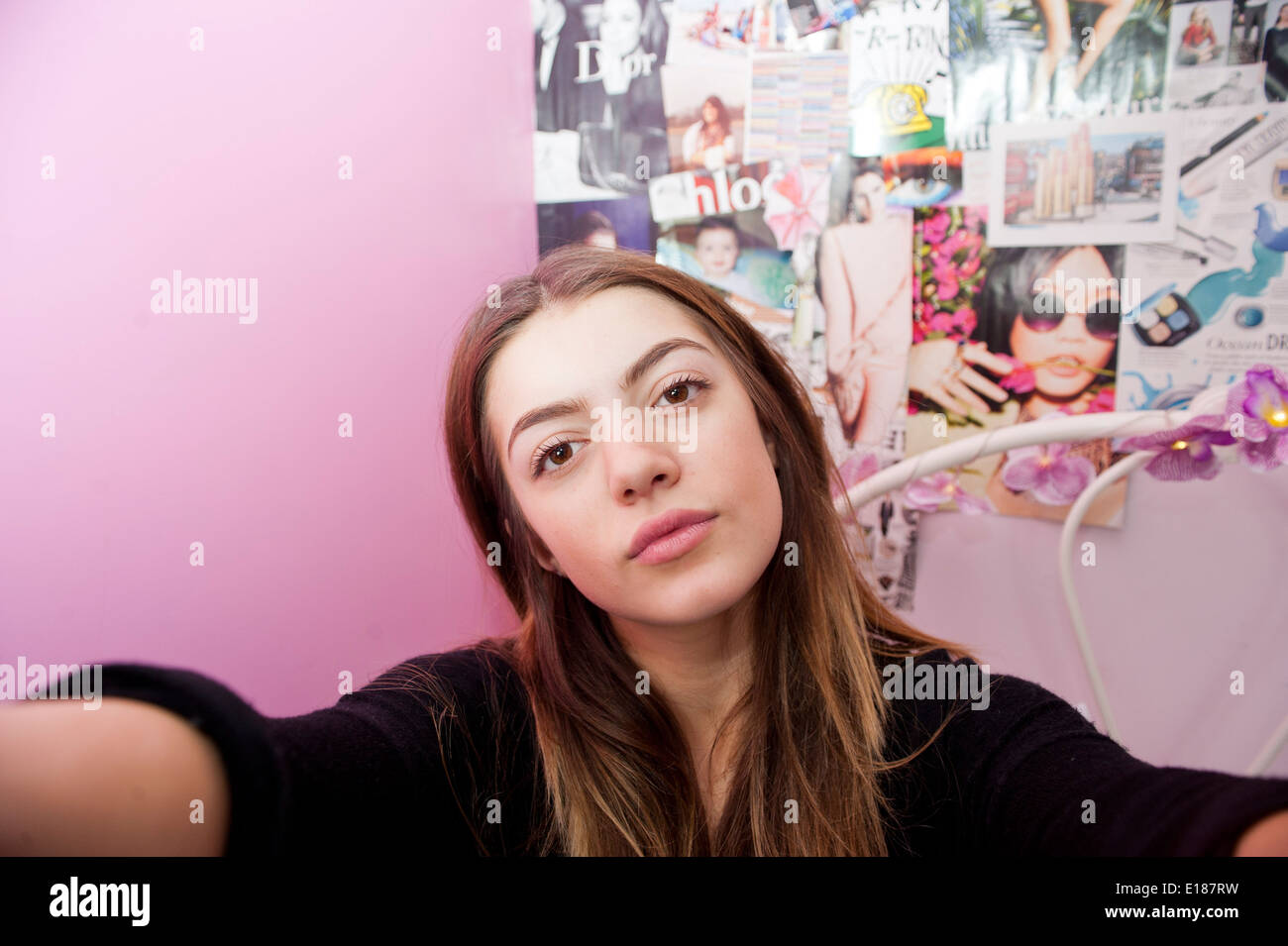 Teenage 13 year old girl posing for a pretend selfie in her bedroom Stock Photo