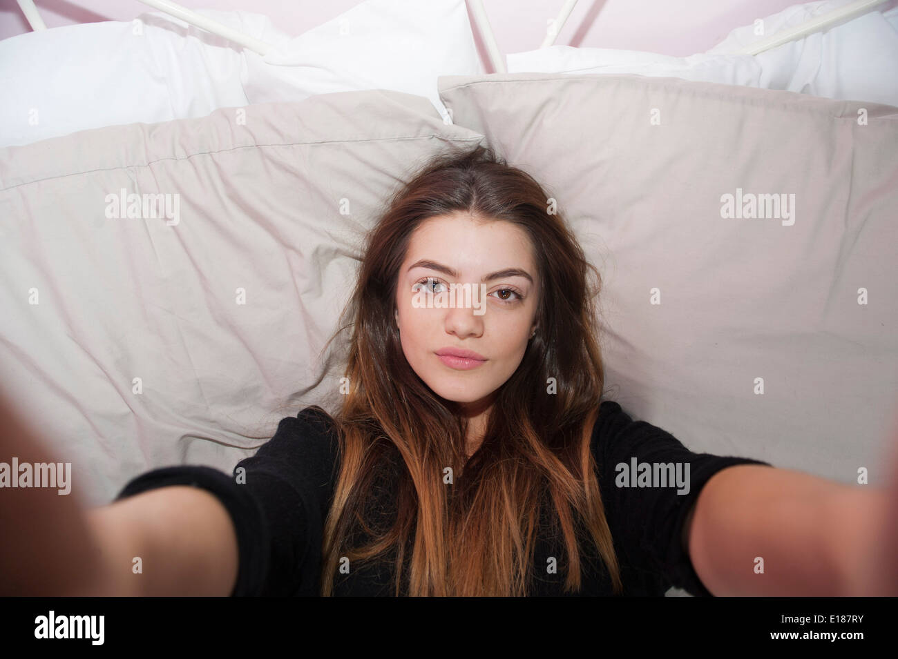 Teenage 13 year old girl posing for a pretend selfie in her bedroom Stock Photo