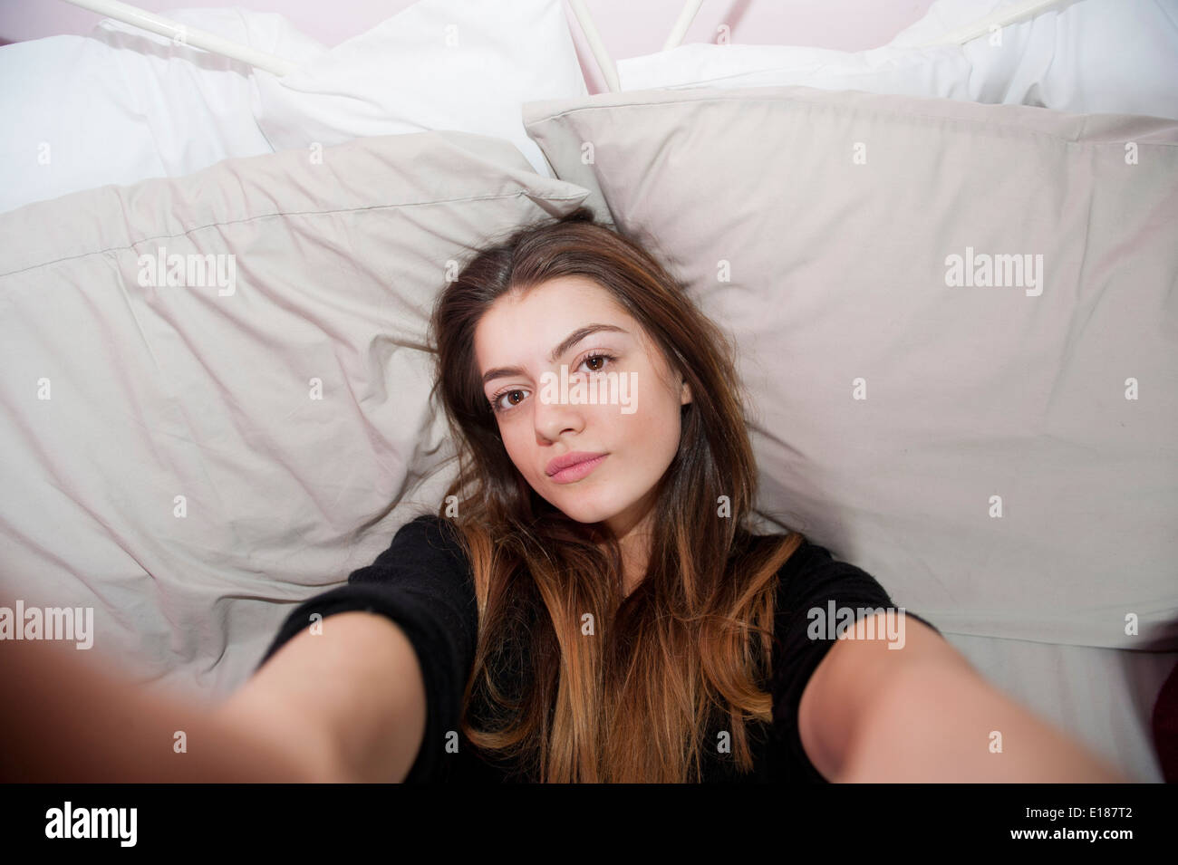 Teenage 13 year old girl posing for a pretend selfie in her bedroom Stock Photo