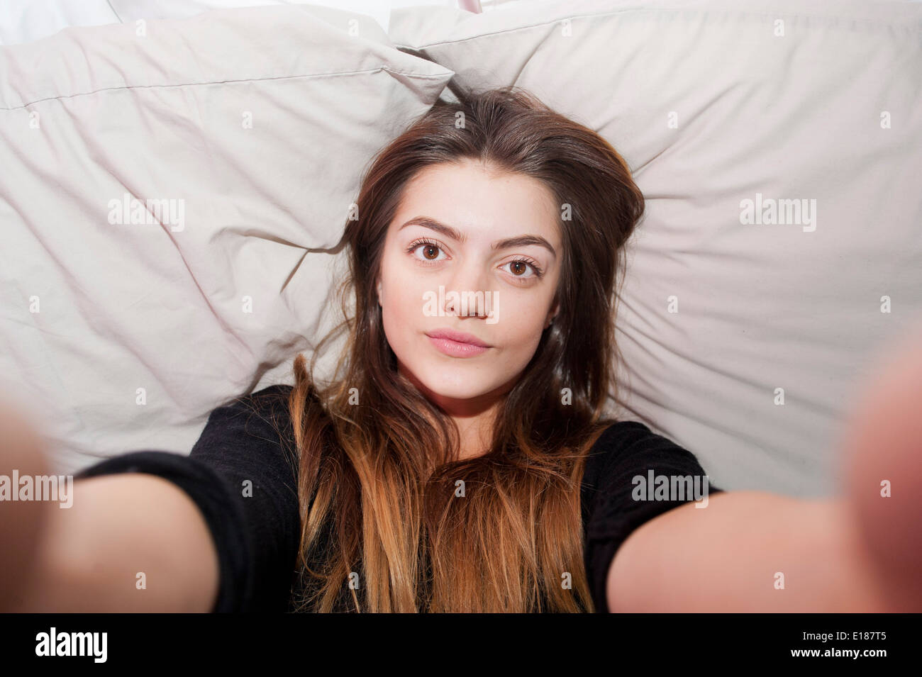 Teenage 13 year old girl posing for a pretend selfie in her bedroom Stock Photo