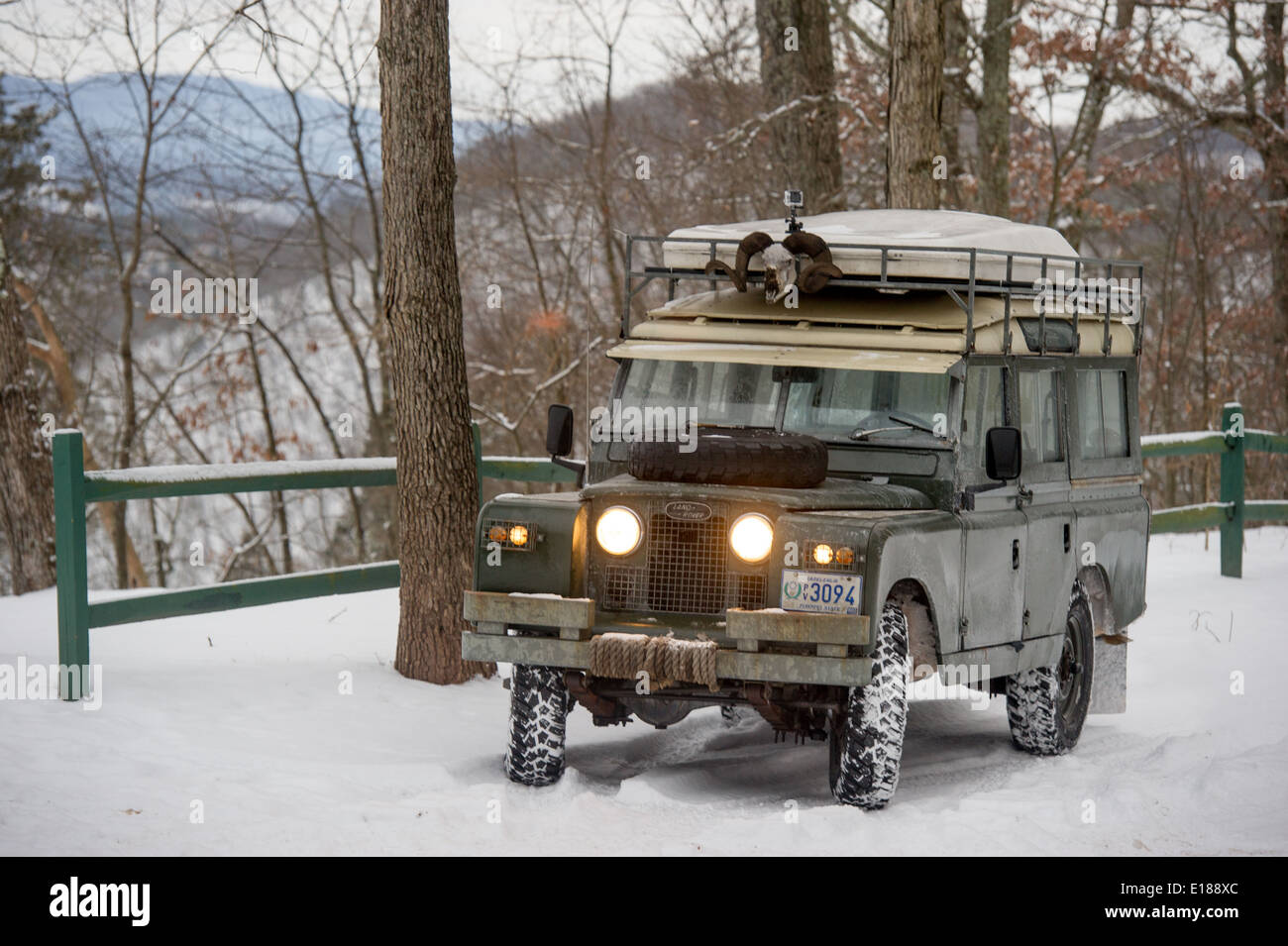 Vintage Land Rover parked near green fence with headlights on, in Green Ridge State Forest in Western Maryland, USA Stock Photo
