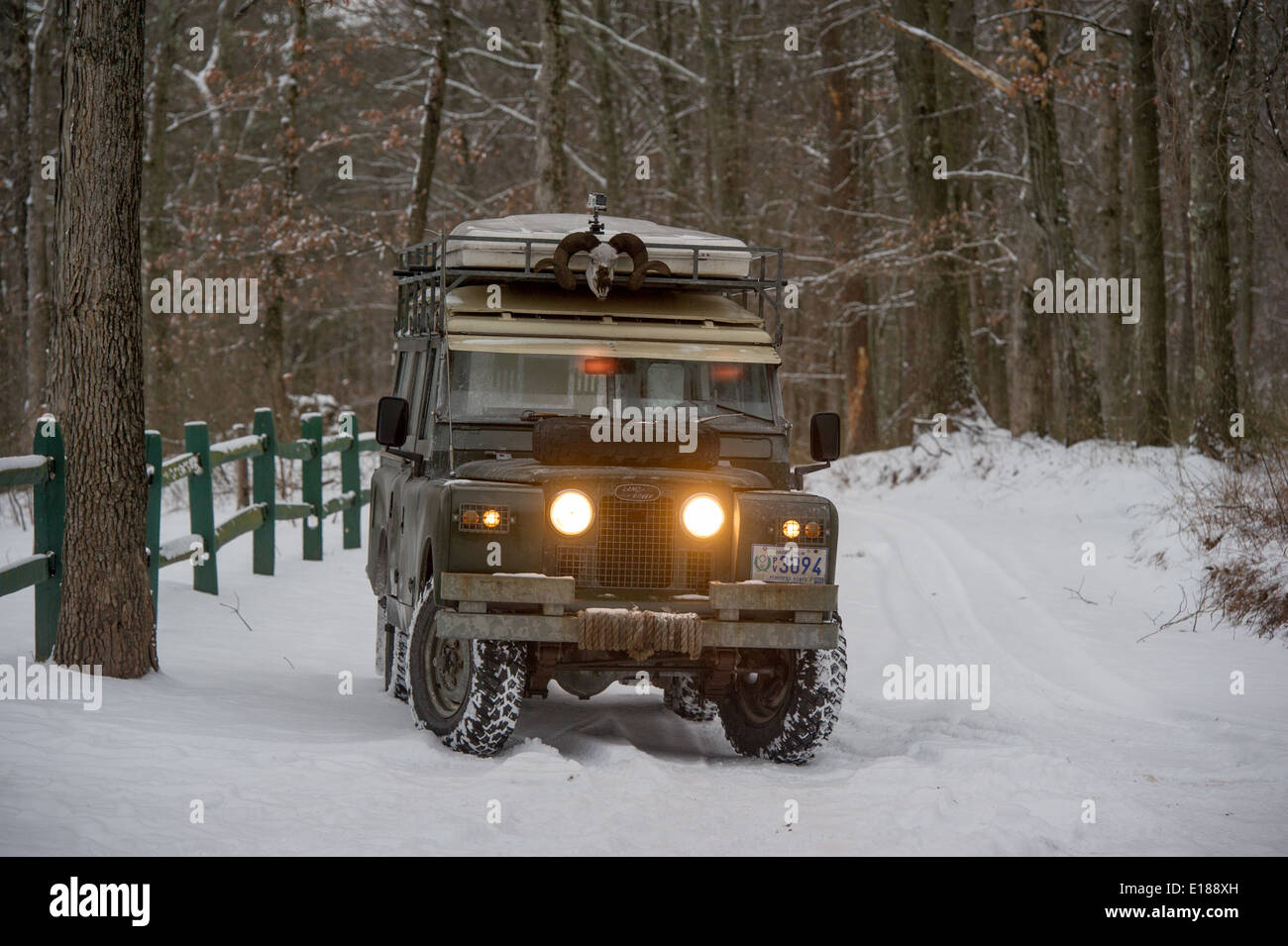 Vintage Land Rover parked near green fence with headlights on, in Green Ridge State Forest in Western Maryland, USA Stock Photo