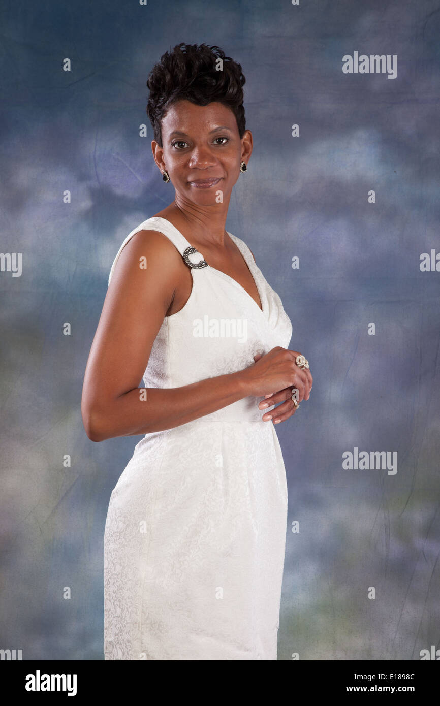 Pretty black woman in white dress, standing and smiling at the camera Stock Photo