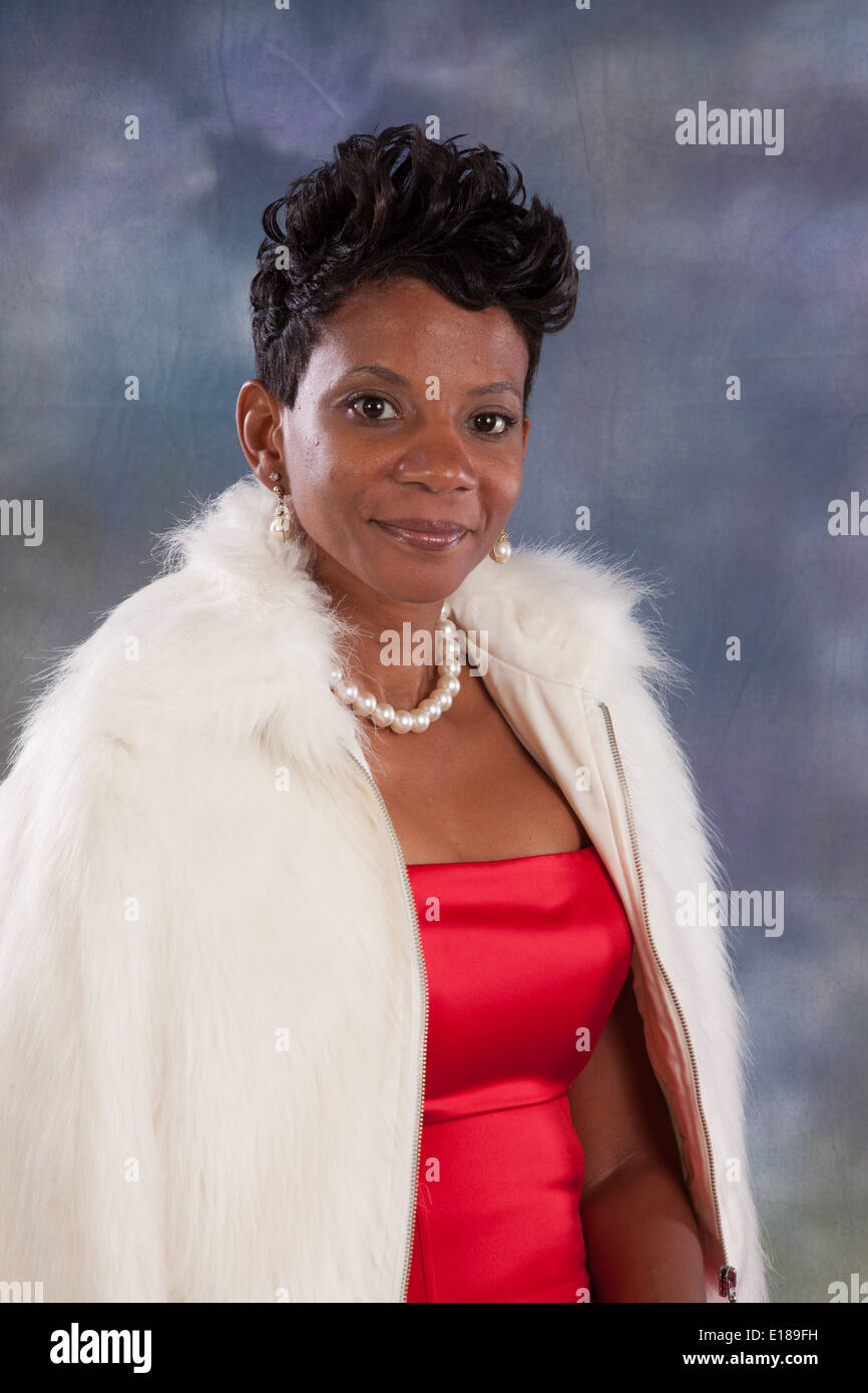 Pretty black woman in red dress and white fur coat, smiling at the camera with a friendly, happy smile Stock Photo