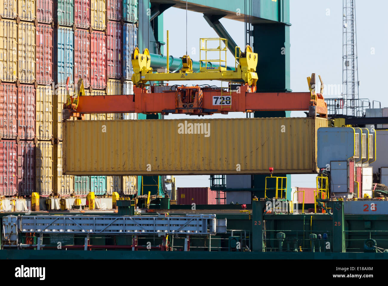 harbor crane lifting a sea container into a cargo ship Stock Photo