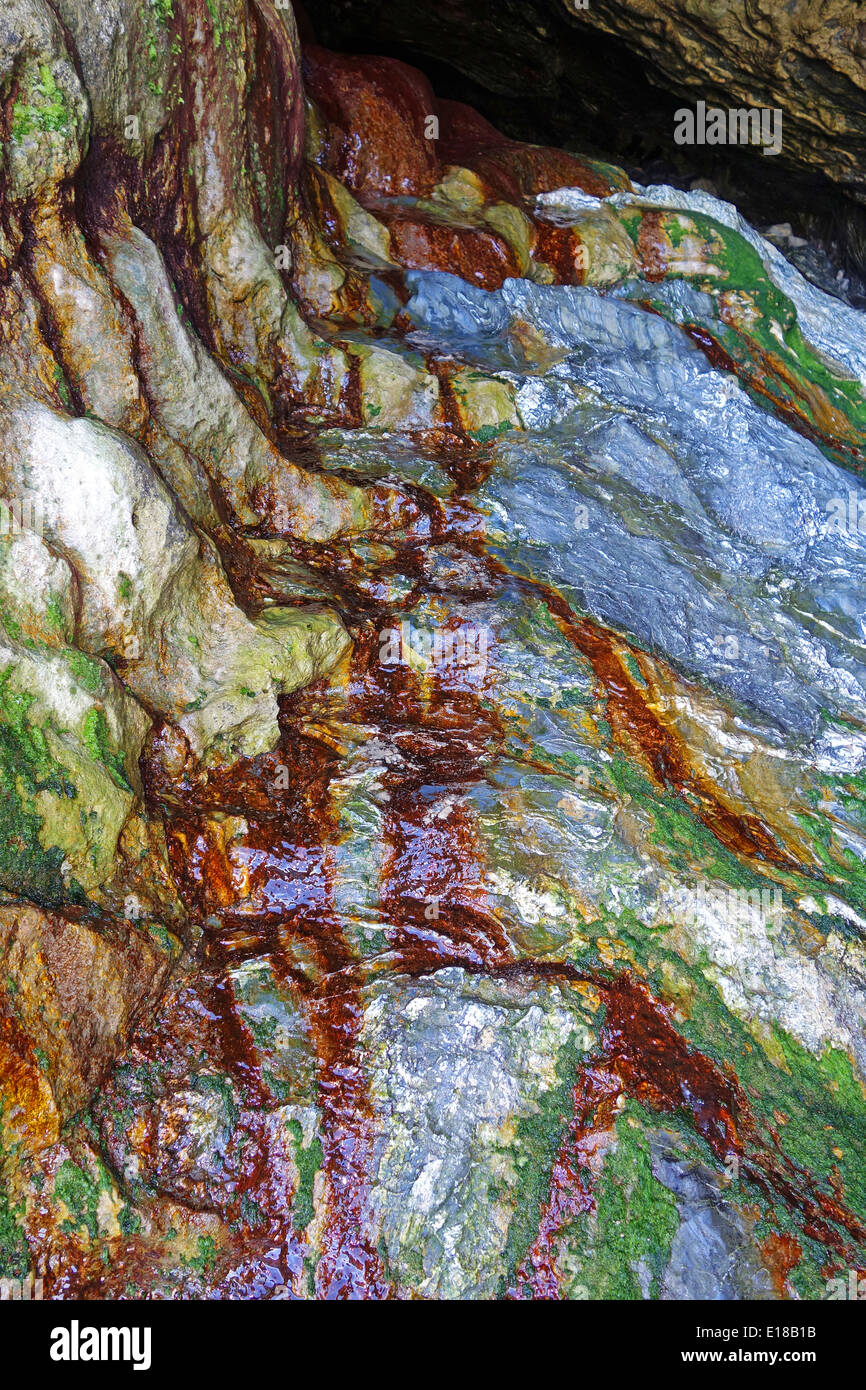 rock colored by rainwater seeping through mineral deposits from the tin mining industry in the ground above Stock Photo