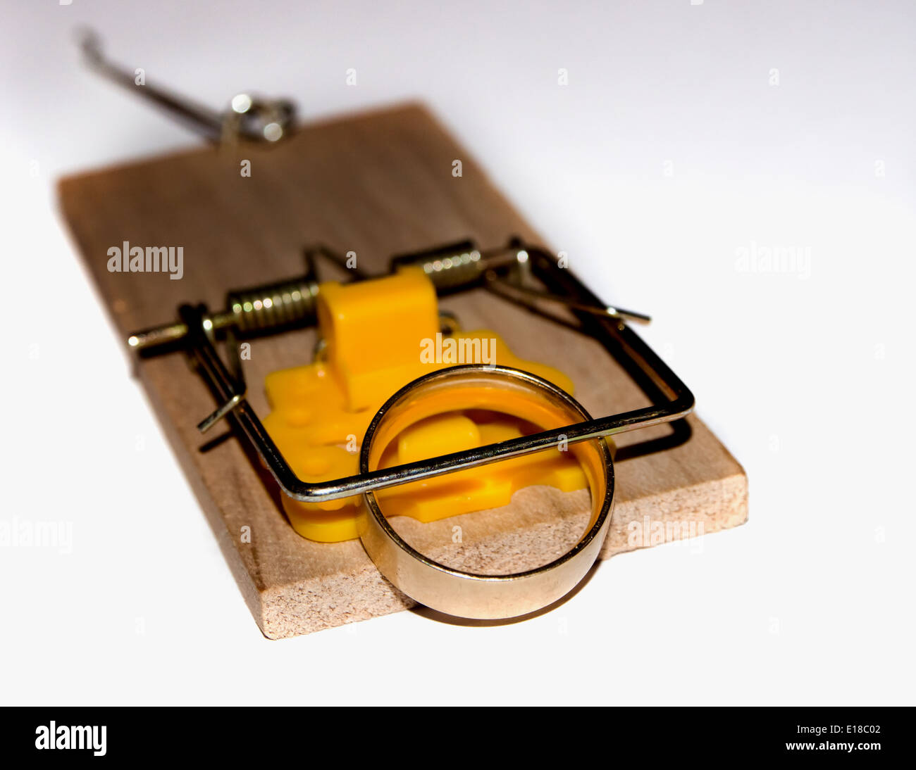 a gold wedding ring trapped in the spring of a mousetrap Stock Photo