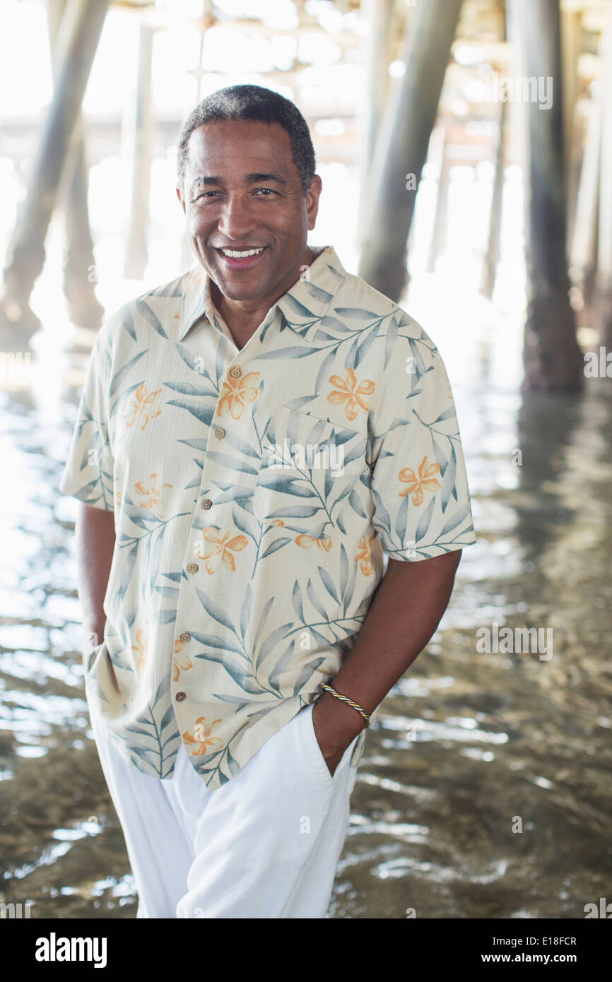 Portrait of confident senior man under pier at beach Stock Photo