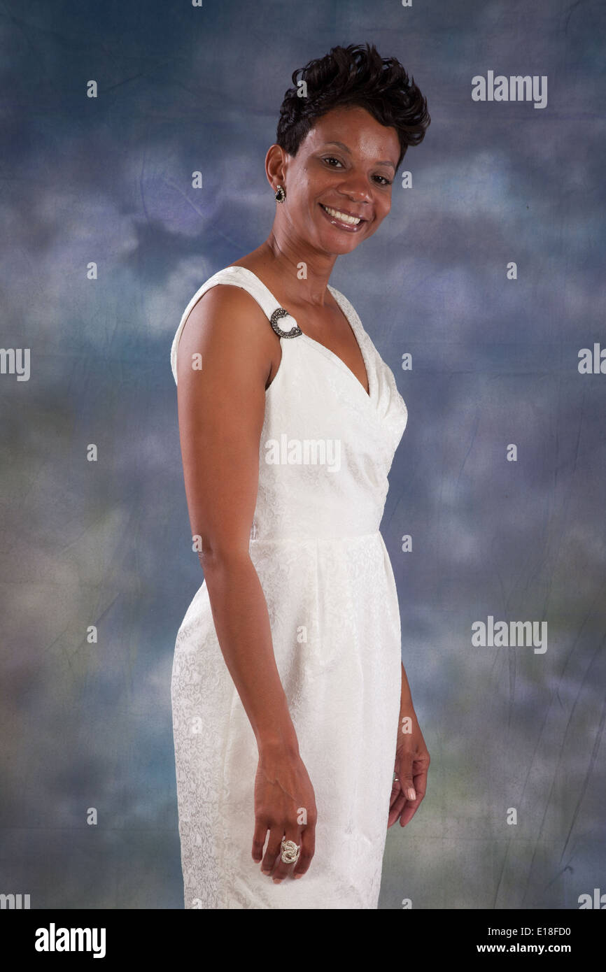 Pretty black woman in white dress, standing and smiling at the camera Stock Photo