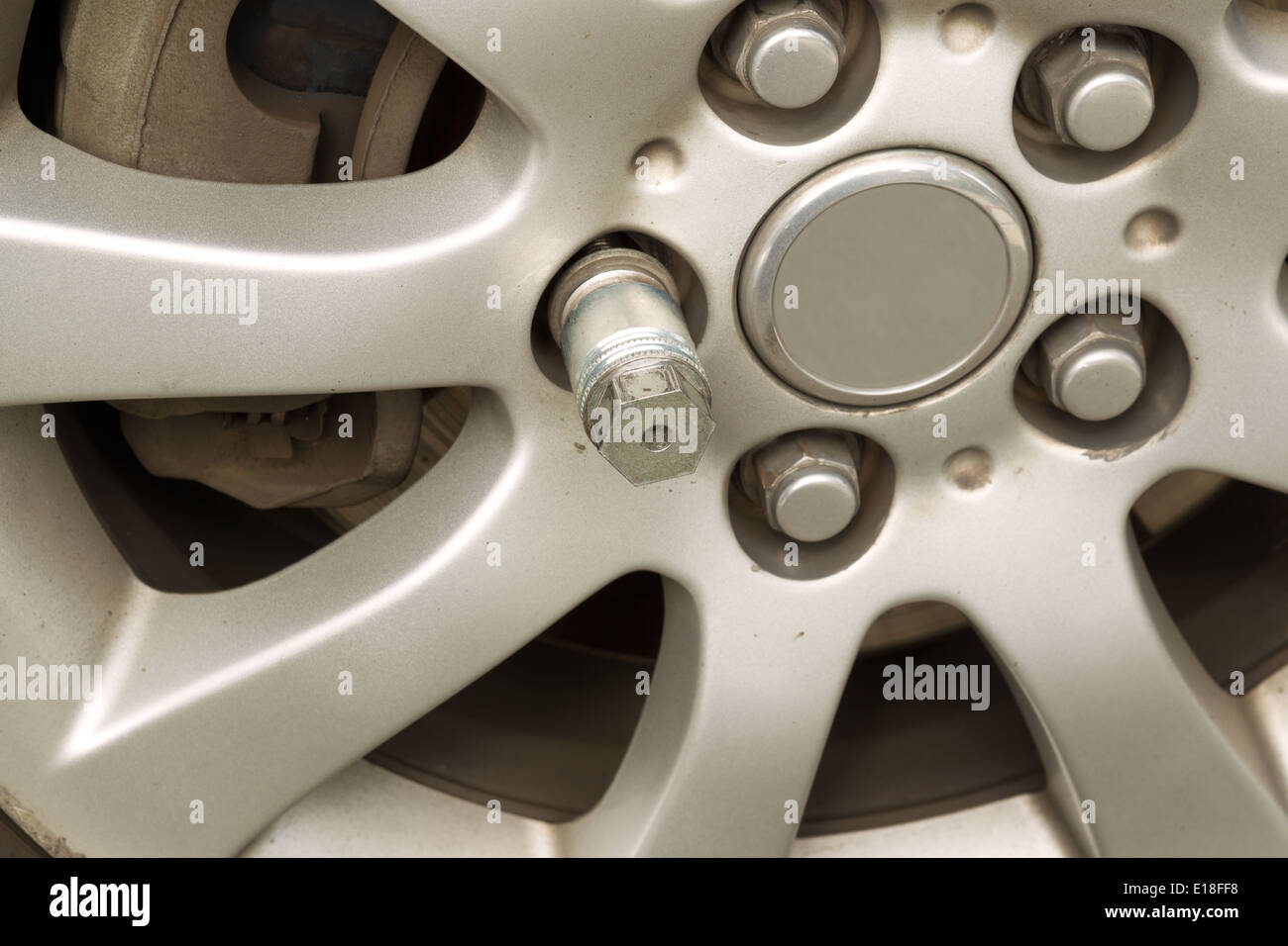 Closeup horizontal photo of locking wheel nut key on car wheel rim Stock Photo
