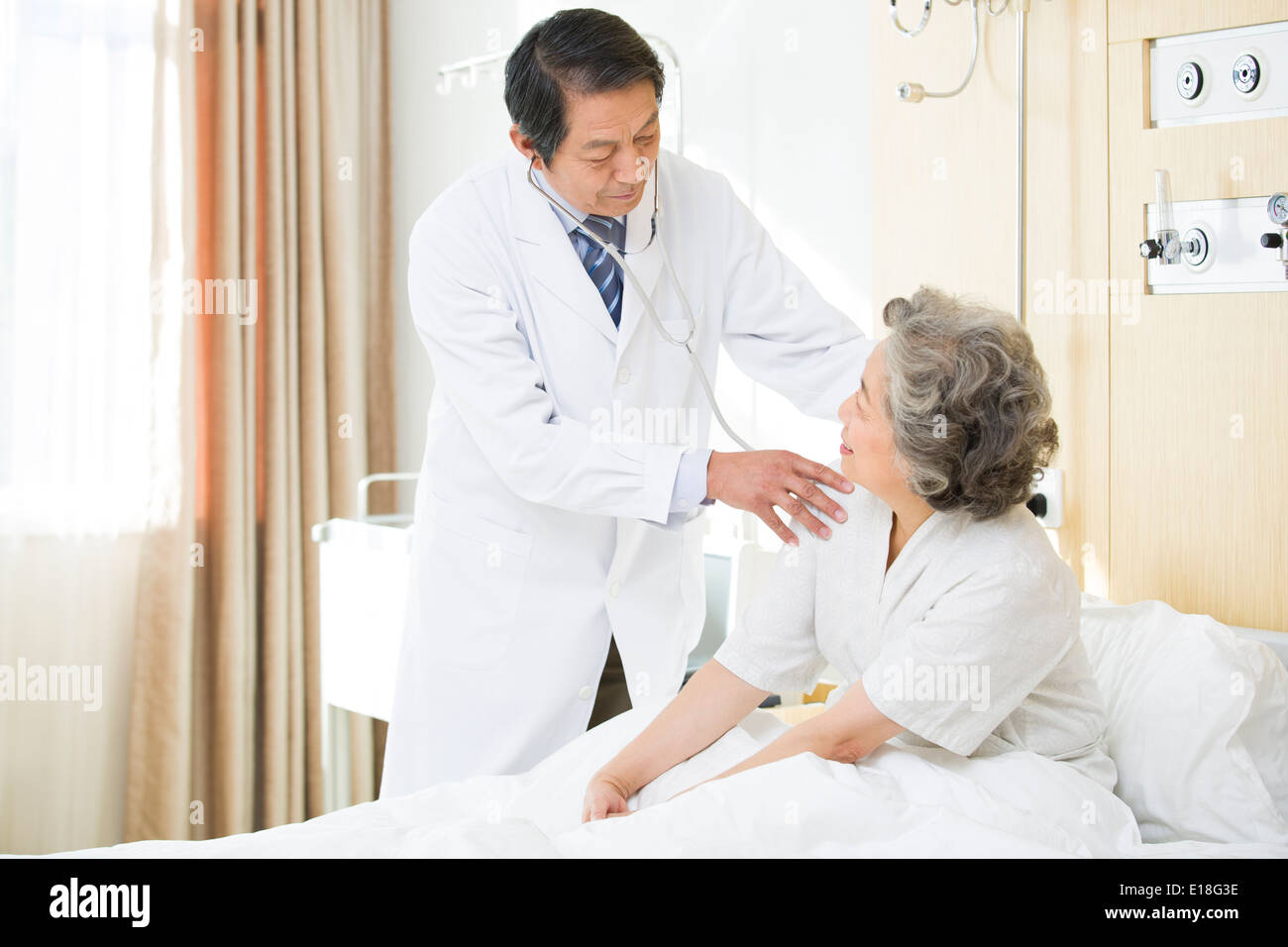 Doctor using stethoscope on patient in hospital Stock Photo - Alamy