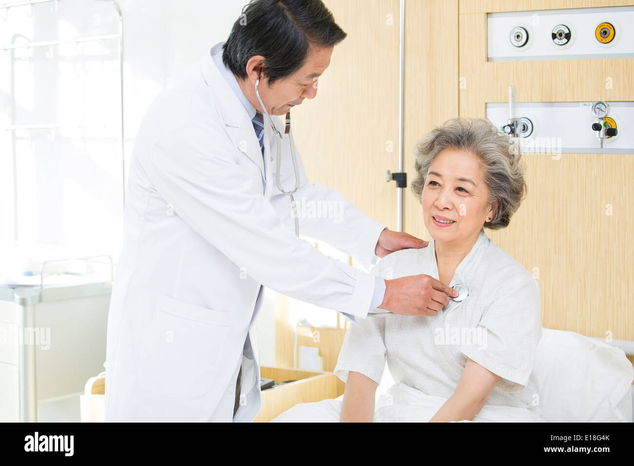 Doctor using stethoscope on patient in hospital Stock Photo - Alamy