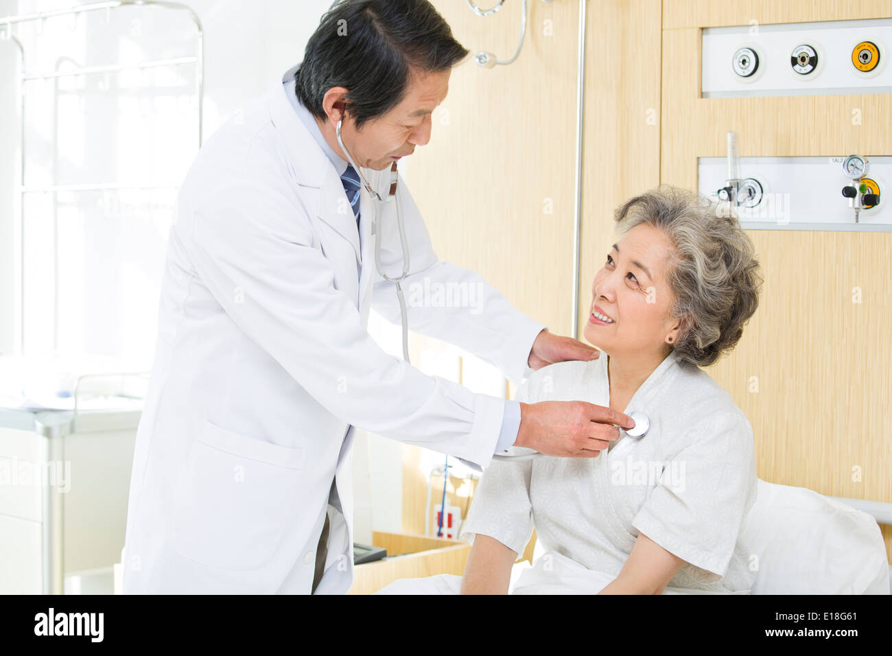 Doctor using stethoscope on patient in hospital Stock Photo - Alamy