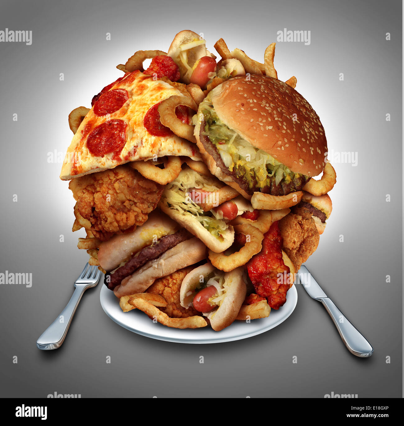 Fast food diet concept served on a plate as a mountain of greasy fried restaurant take out as onion rings burger and hot dogs with fried chicken french fries and pizza as a symbol of compulsive overeating and dieting temptation resulting in unhealthy nutr Stock Photo