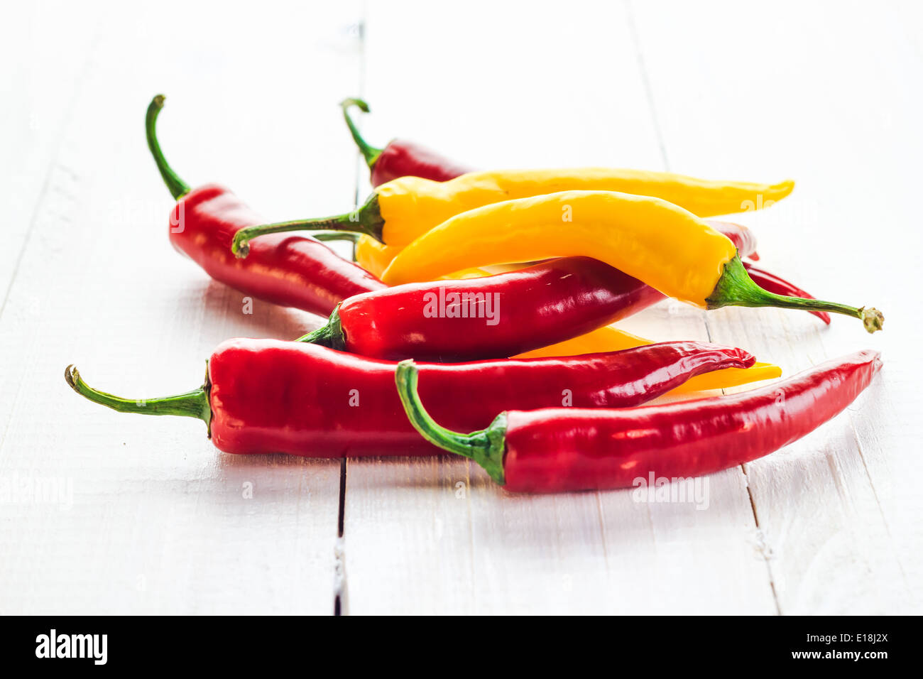Red and yellow chili peppers on a wooden background Stock Photo - Alamy