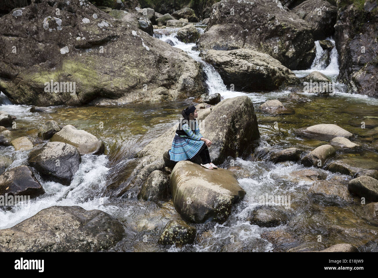 A woman belonging to the H'Mong ethnic group sitting on rocks in the ...