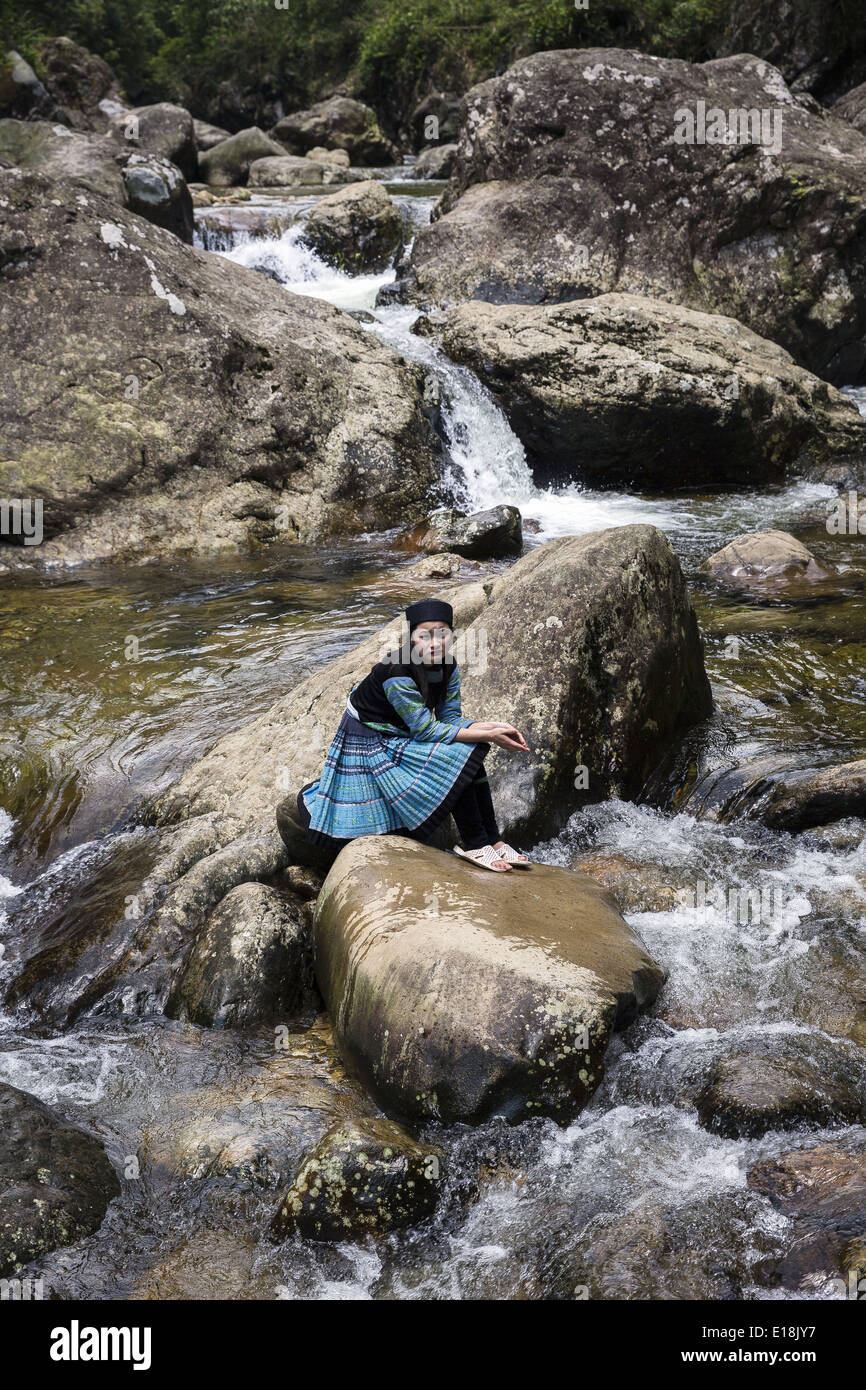 A woman belonging to the H'Mong ethnic group sitting on rocks in the ...