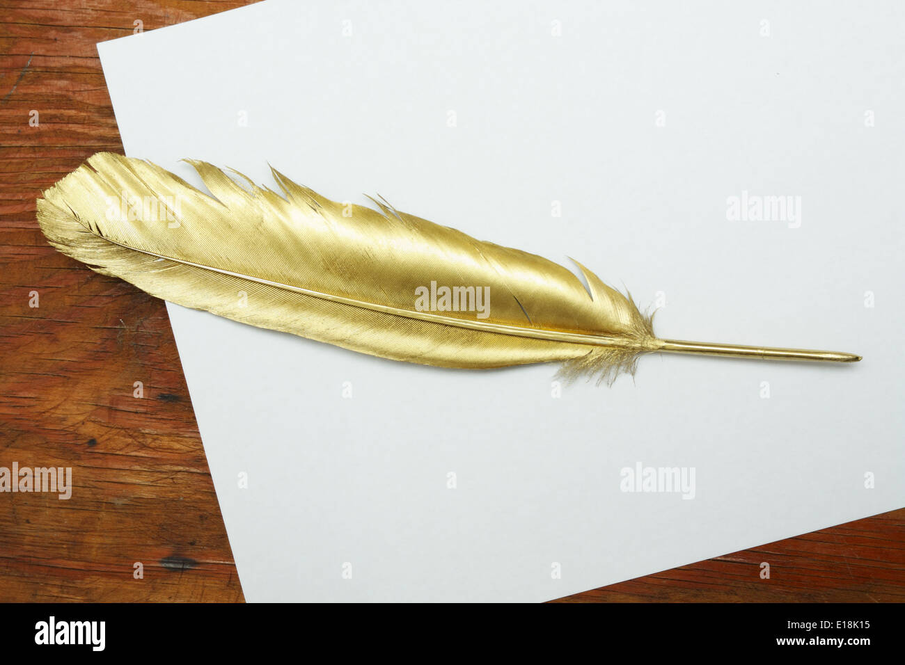 Gold quill pen on a white paper and wooden table Stock Photo