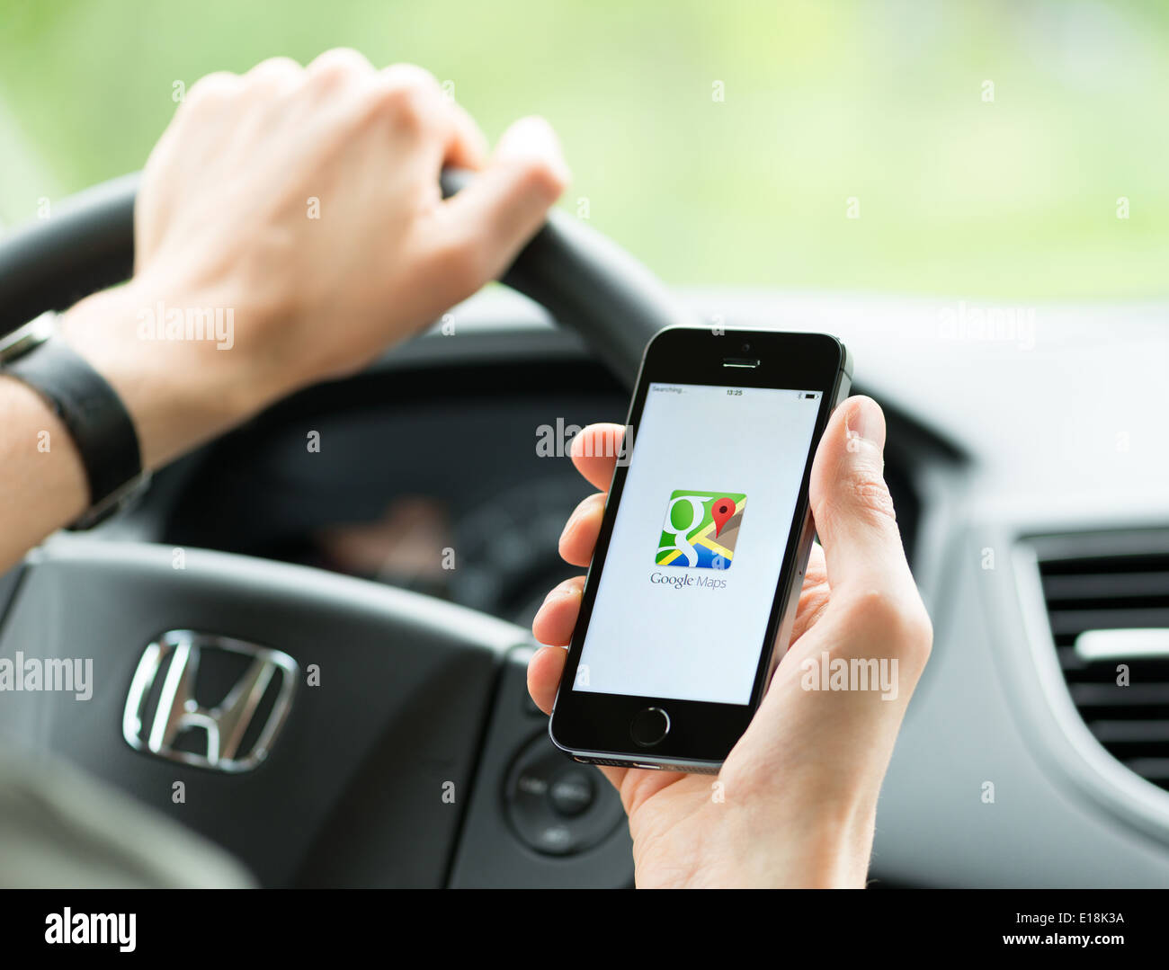 Man in the car planning a route using a Google Maps application on Apple iPhone 5S. Stock Photo