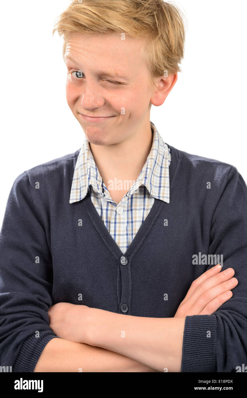 Playful boy winking while standing arms crossed against white background Stock Photo
