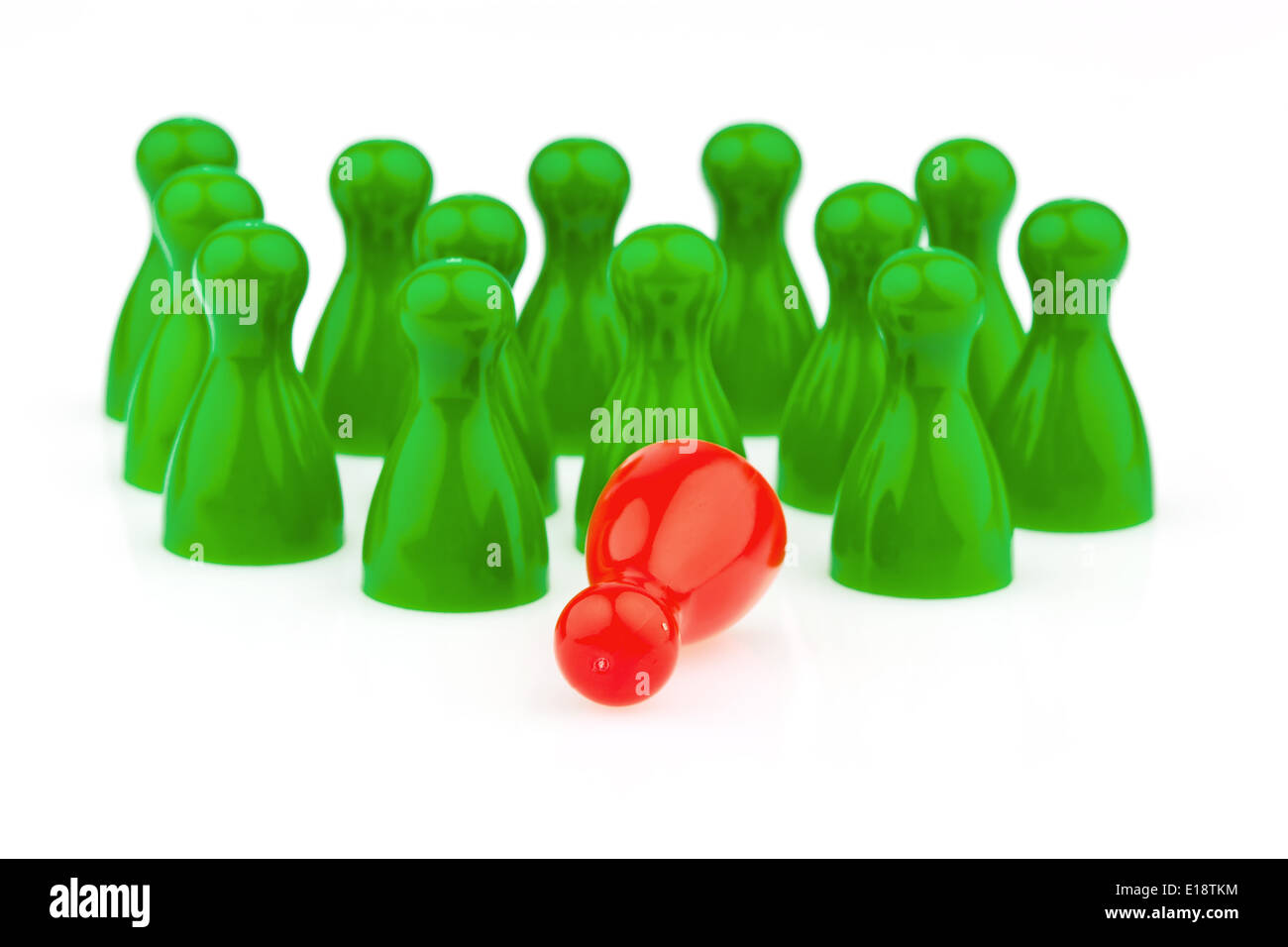 Rote und grüne Spielfiguren. Mobbing, Einsamkeit und Außenseiter im Team. Stock Photo