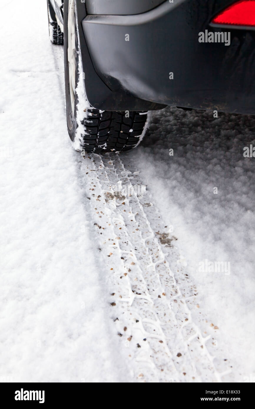 Spuren von Winterreifen im Schnee auf der Fahrbahn einer Straﬂe Stock Photo