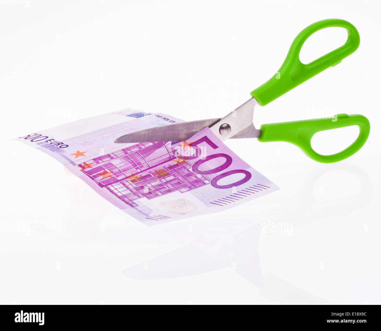 Von einem Euro Geldschein wird mit einer Schere ein Stueck abgeschnitten. Symbol Steuern und Abgaben. Stock Photo