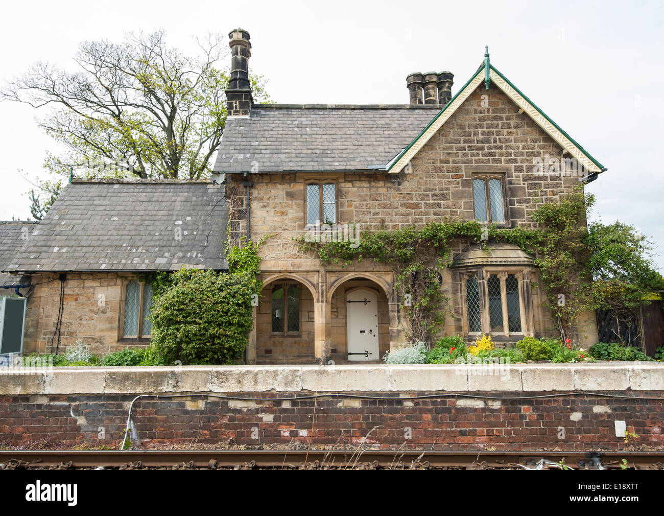 Traditional english railway station house on platform next to track Stock Photo