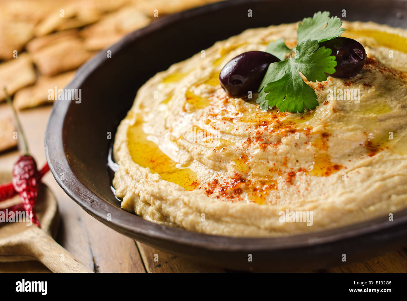 A bowl of creamy hummus with olive oil and pita chips. Stock Photo