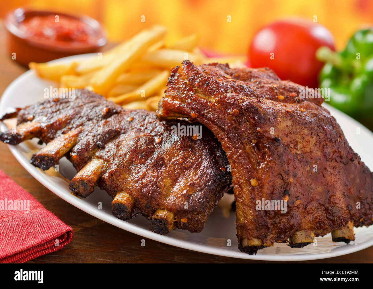 Barbecued pork baby back ribs against a hardwood fire background. Stock Photo