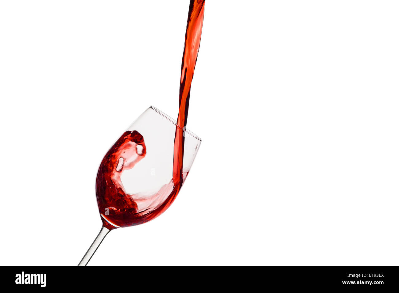 In ein Glas wird schwungvoll roter Wein eingeleert. Rotwein im Rotweinglas Stock Photo
