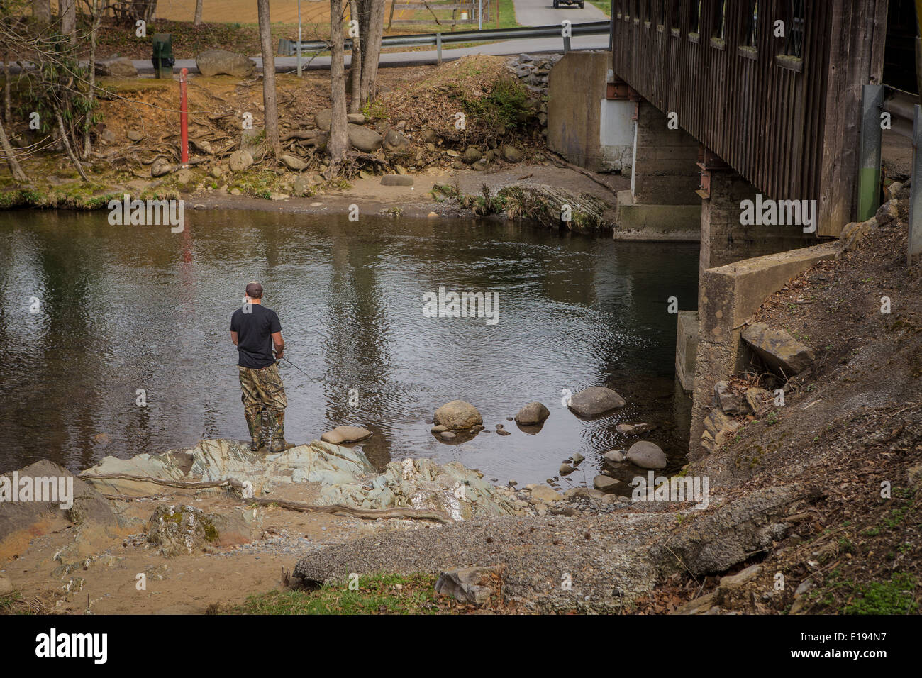 A man fishes on Little Pigeon River, by the Emerts Cove Covered Bridge in Pittman Center, Tennessee Stock Photo