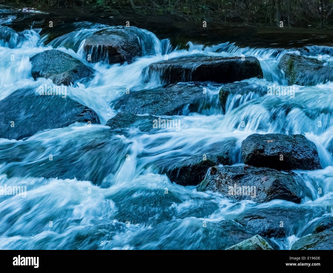 Ein Bach mit Steinen und fliessendem Wasser. Landschaft erleben in der Natur. Stock Photo