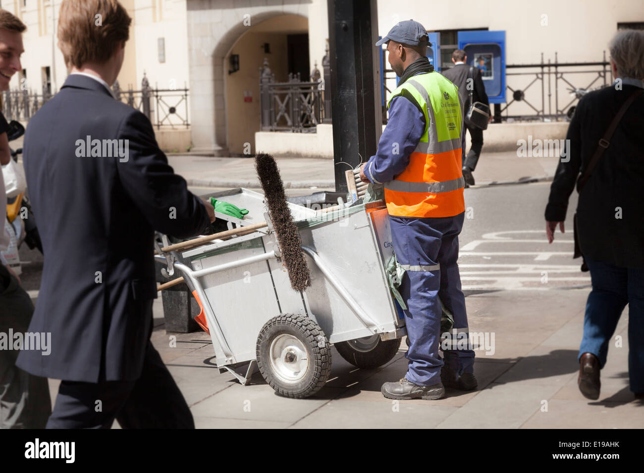 Street cleaner with cart amidst the bustle of a London street. Stock Photo