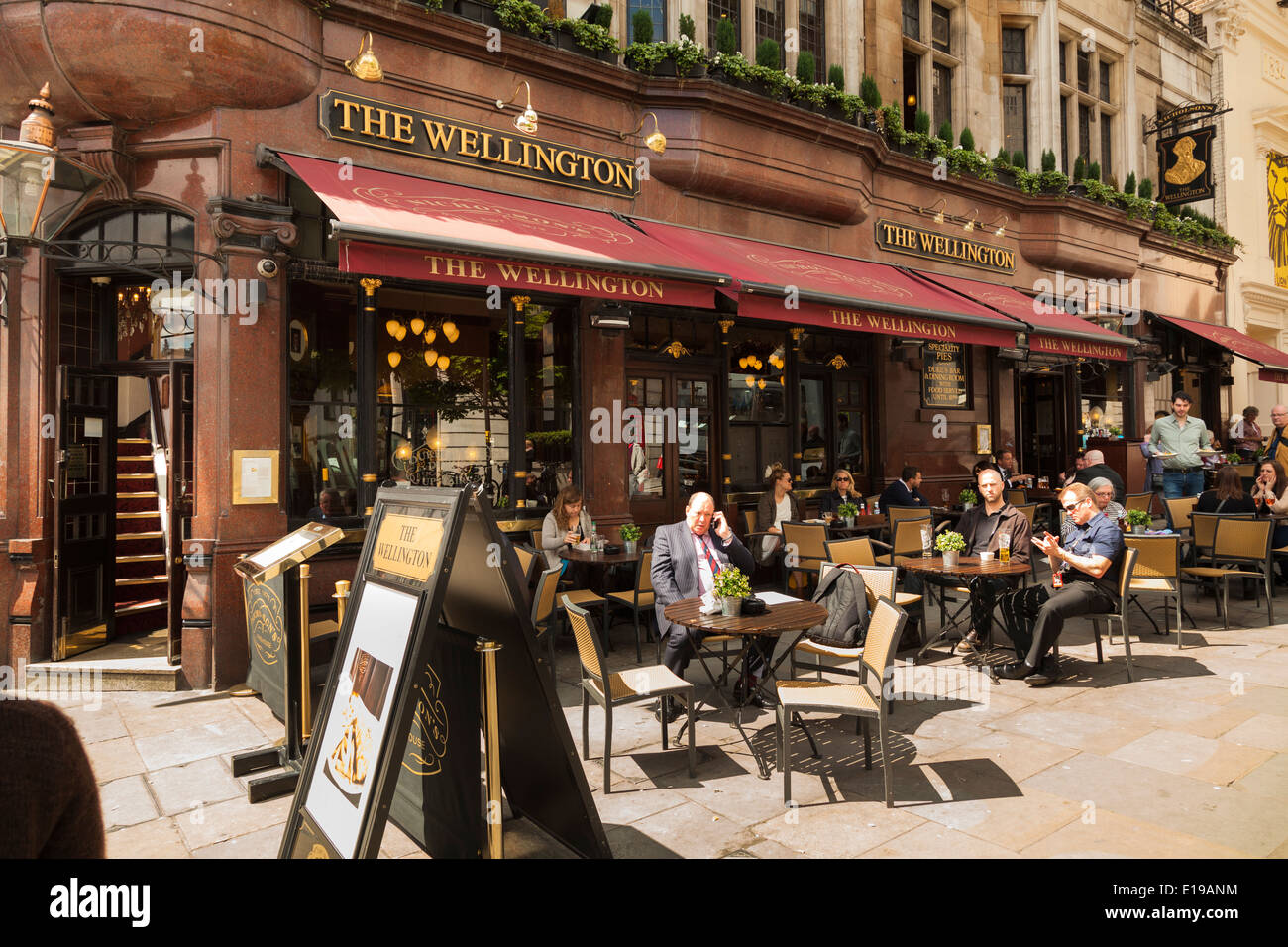 Customers sitting at sunny tables outside wellington pub in the Strand London. Stock Photo
