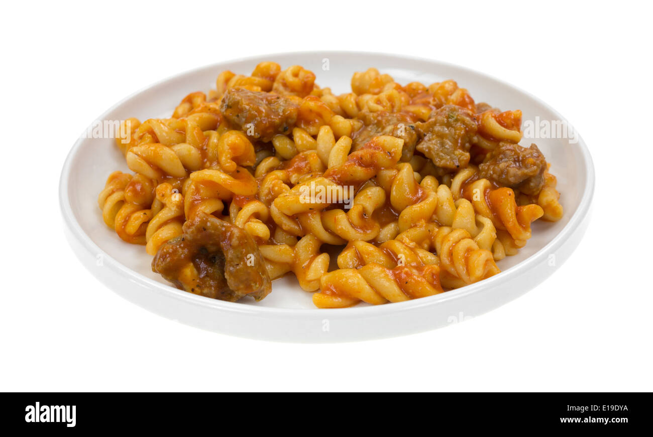 A cooked serving of spiral pasta in a tomato sauce with small chunks of Italian sausage TV dinner on a small plate. Stock Photo